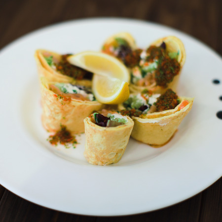 small rolls of thin pancakes with salted red fish