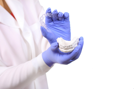 Close-up shot of doctors hands in gloves holding silicone mouth guard.