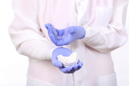 Close-up shot of doctors hands in gloves holding silicone mouth guard.