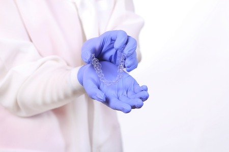Close-up shot of doctors hands in gloves holding silicone mouth guard.