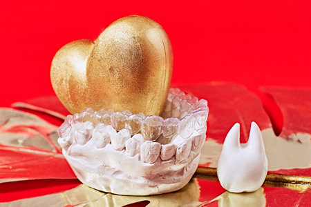 Heart of gold on a red background in invisible dental aligners or braces aplicable for an...