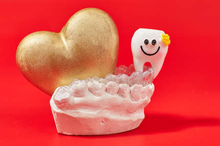 Heart of gold on a red background in invisible dental aligners or braces aplicable for an...