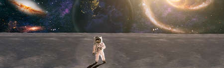 Astronaut looks up at an alien sun that illuminates the barren world he stands on.
