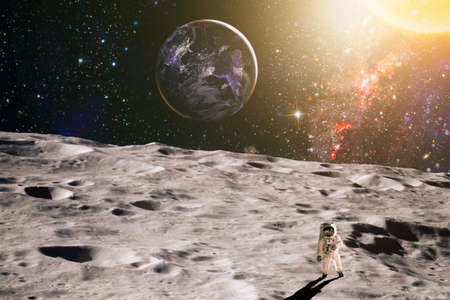 Astronaut looks up at an alien sun that illuminates the barren world he stands on.