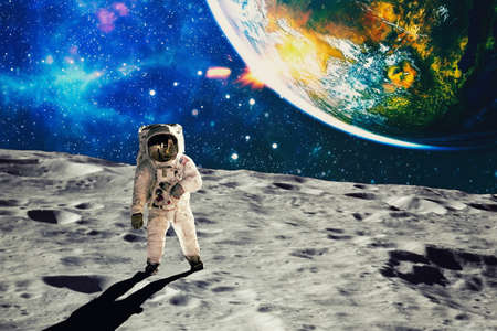 Astronaut looks up at an alien sun that illuminates the barren world he stands on.の写真素材