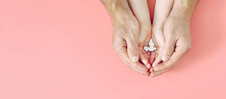 Adult and child hands holding white dove bird on pink background, international day of peace or world peace day concept, sustainable consumption, csr responsible business conceptの写真素材