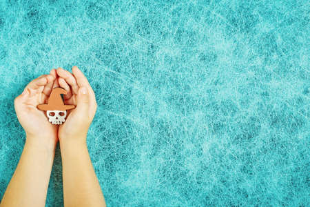 Holiday helloween on a cobweb background with a skull in the hands of a childの写真素材