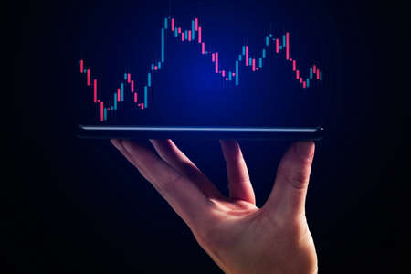Stock market, Business growth, progress or success concept. Hand of Businessman or trader is showing a growing virtual hologram stock on smartphoneの写真素材