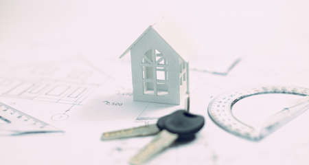 Keys and wooden house model against white background