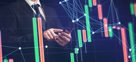 Man using smartphone with graphs analysis candle line and foreign currency rate on bokeh colors...
