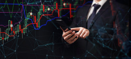Man using smartphone with graphs analysis candle line and foreign currency rate on bokeh colors...