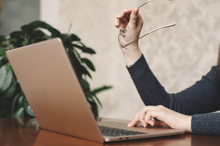 Girl thinking with glasses in her hands behind a laptop Trend analysisの写真素材