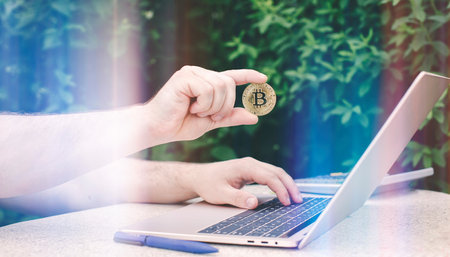Laptop with chart and bitcoin in hands. Cryptocurrency gold coin, stock exchange graph