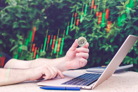 Laptop with chart and bitcoin in hands. Cryptocurrency gold coin, stock exchange graphの写真素材