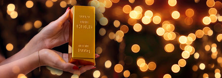 Girl holding gold bar, Business graph background. Buying gold investmentの写真素材