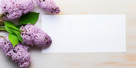 Table with lilac purple flower, white paper top view, flat lay, minimal style.の素材