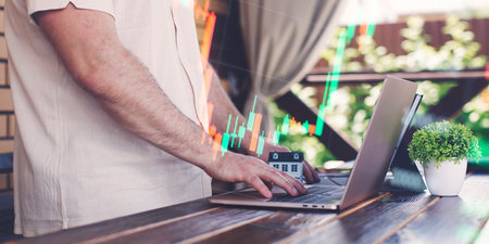 Businessman uses laptop to invest in real estate with growth stability chart.