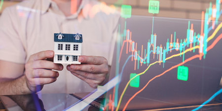 Businessman uses laptop to invest in real estate with growth stability chart.の写真素材