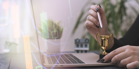 Triumph in Real Estate Investment: A Trophy Representing Success, Model House, and a Laptop