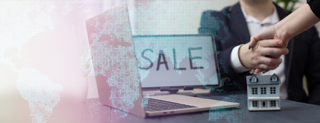 Handshake Agreement in Real Estate Sale with Laptop and Model Houseの写真素材