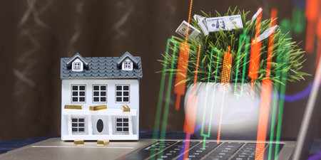 Market analysis and real estate investment workspace with miniature house, gold bars