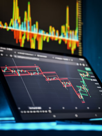 Tablet screen displays a digital asset trading chart with high volatility and candlestick patterns,...