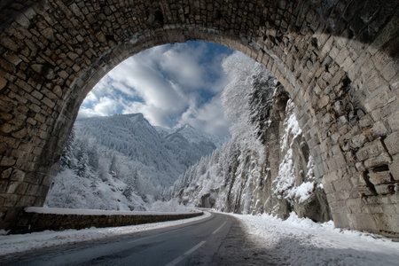 Scenic Snowy Mountain Road Through Stone Archway .Generative AIの素材