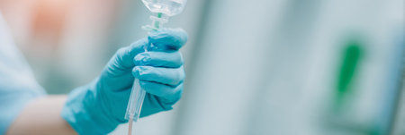 Nurse installing IV drip, close-up on gloved hands, clean hospital environment. Generative AIの素材
