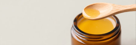 Wooden spoon scooping yellow balm from amber glass jar. Generativeの素材