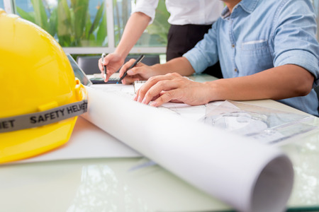 Hands of engineer working with the tool on project drawings background at construction siteの写真素材