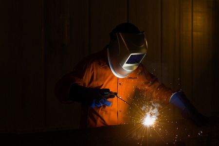 Welder with personal protective equipment and protective mask welding steel pipe in factory.の写真素材