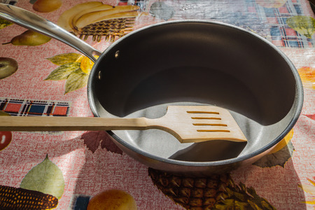 Frying pan with wooden spoon on the kitchen tableの写真素材