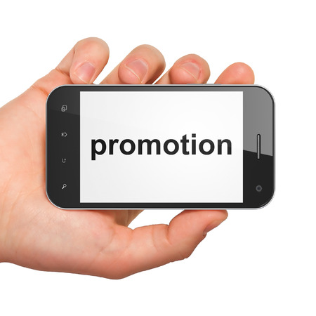Advertising concept: hand holding smartphone with word Promotion on display. Mobile smart phone on White background, 3d renderの写真素材