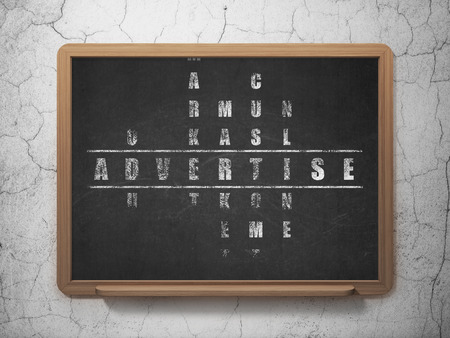 Marketing concept: Painted White word Advertise in solving Crossword Puzzle on School Board background, 3d renderの写真素材