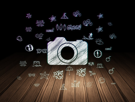 Tourism concept: Glowing Photo Camera icon in grunge dark room with Wooden Floor, black background with  Hand Drawn Vacation Iconsの写真素材