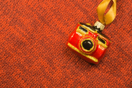 Christmas tree decoration on textile background. Christmas tree toy in a form of a camera. copy...