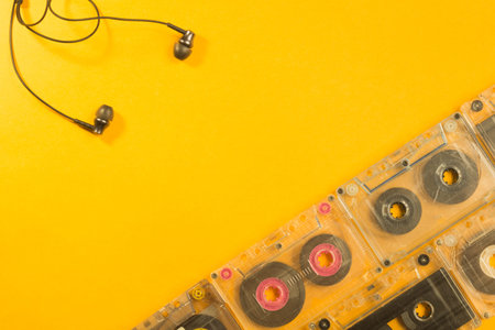 Earphones and retro cassette on yellow background. copy space