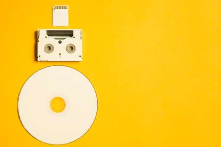 Compact disc and memory card on yellow background. digital video cassette. copy spaceの写真素材