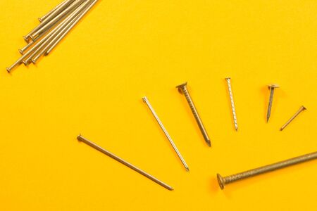 Metal nails isolated on yellow backgroundの写真素材