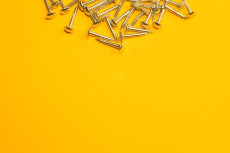 Metal nails isolated on yellow backgroundの写真素材