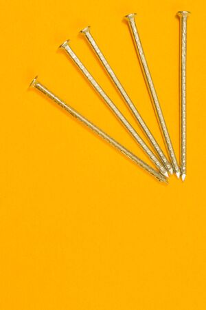 Metal nails isolated on yellow backgroundの写真素材