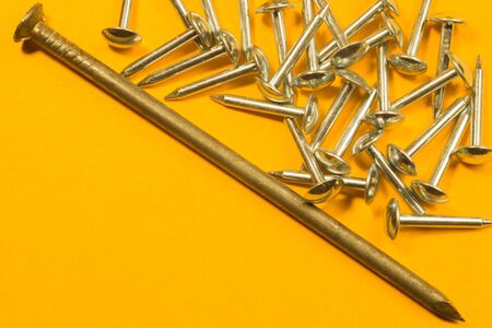 Metal nails isolated on yellow backgroundの写真素材