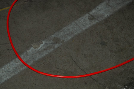 Red electric power cable. red wire lies on the ground. mess on cement floor. industrial backgroundの写真素材