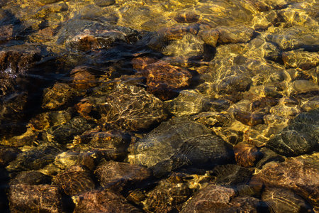 Shiny transparent water. clear water with pebbles and stone on the bottom. shining reflections of...