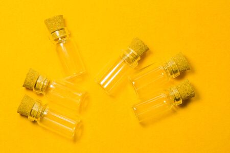 Empty little bottles with cork stopper isolated on yellow. glass vessels. transparent containers. test tubesの写真素材