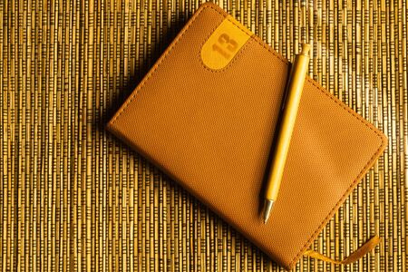 Diary and pen on a wooden bamboo background. notebook and pen top view. copy spaceの写真素材