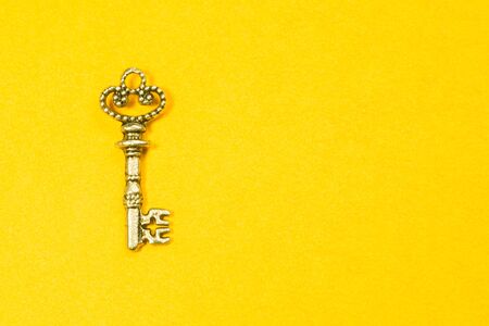 Old key isolated on yellow background. safety and security conceptの写真素材