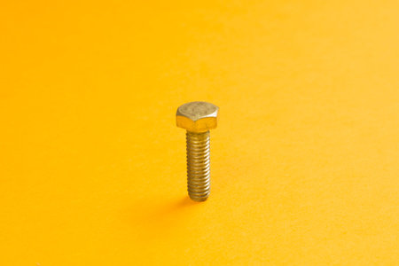Steel screw on a yellow background. working tools