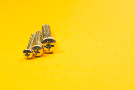 Steel screw on a yellow background. working tools