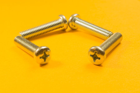 Steel screw on a yellow background. working tools